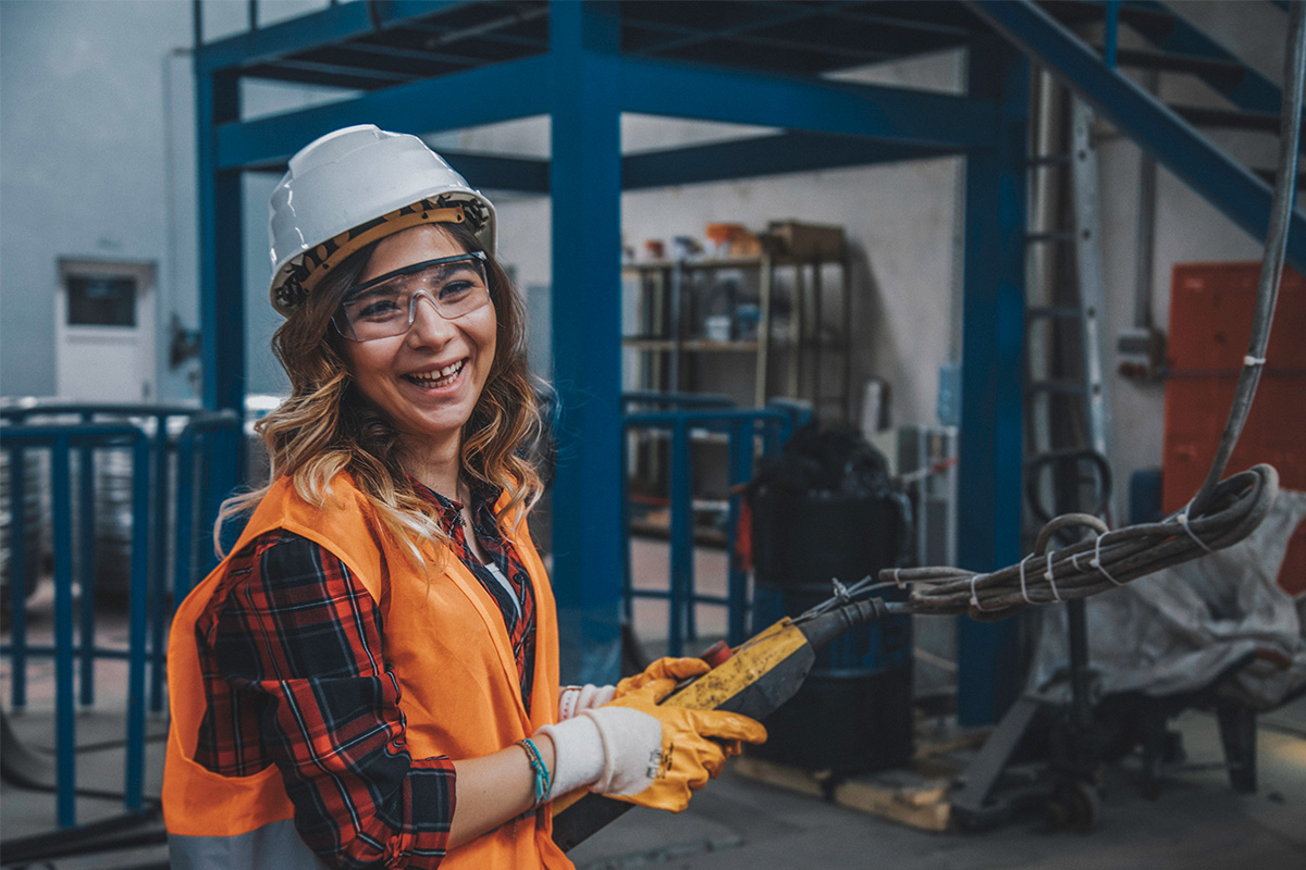 Woman with safety hard hat and vest in workshop