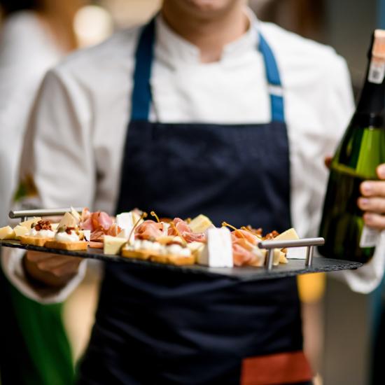 server with tray of canapes and bottle in hand